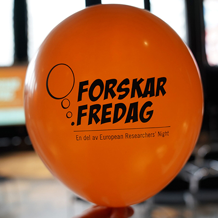 Orange ballong med texten "Forskarfredag" tryckt på. Foto. 