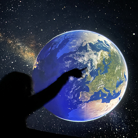 Barn pekar på vår planet Jorden som projiceras i planetariet. Foto. 