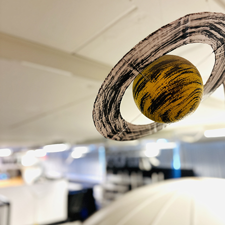 Modell av planeten Saturnus som hänger i taket på vattenhallen. Foto. 