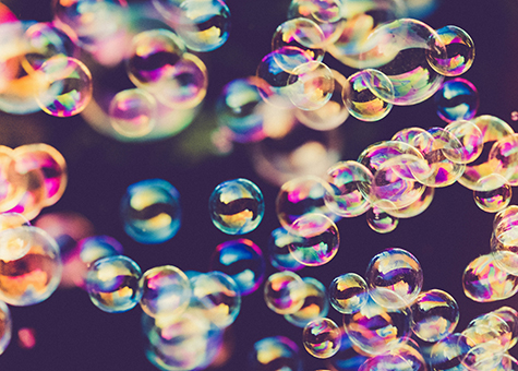 Bubblor i regnbågens färger mot mörk bakgrund. Foto. 